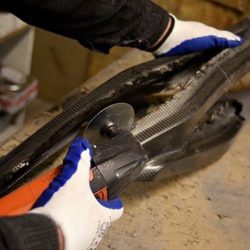 A person is working on a bike frame with gloves on.
