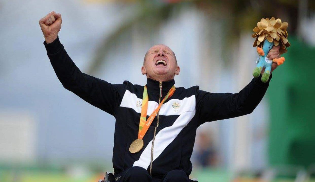 A man celebrating with hands up and wearing a medal
