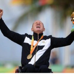 A man celebrating with hands up and wearing a medal