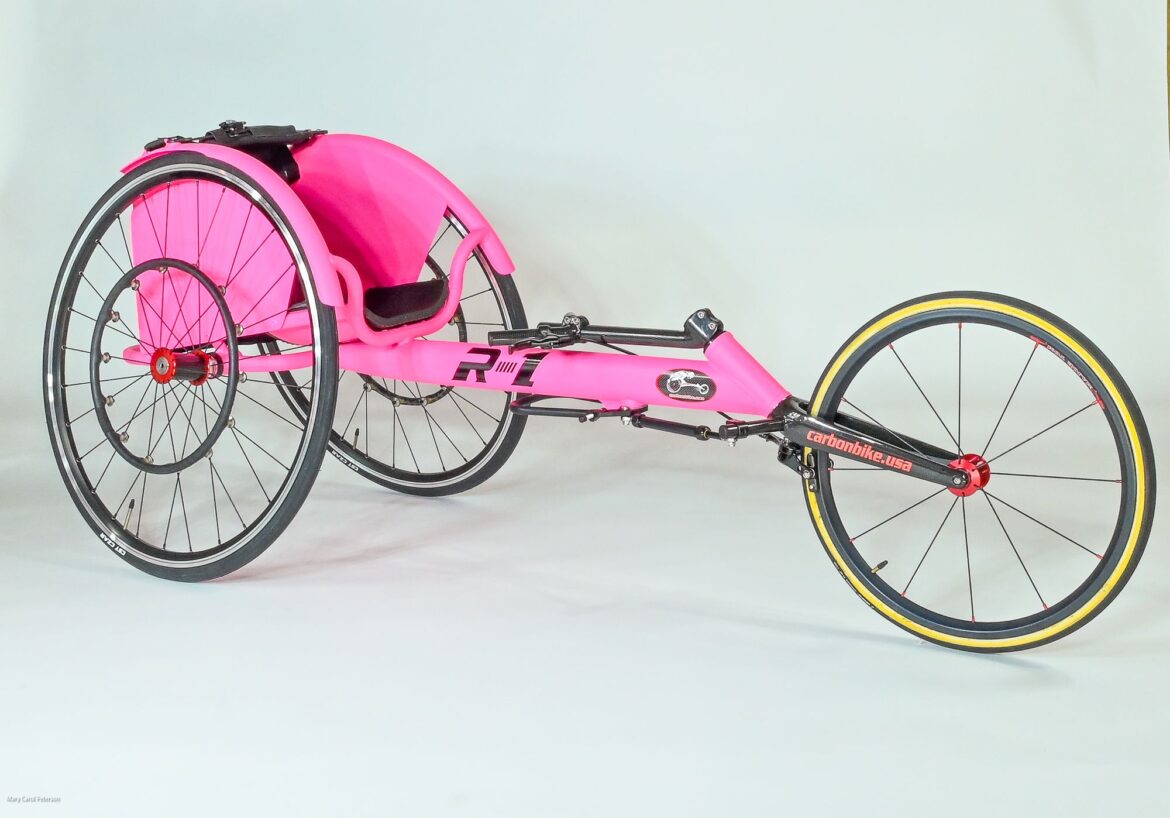 A pink wheelchair with black wheels on a white background.