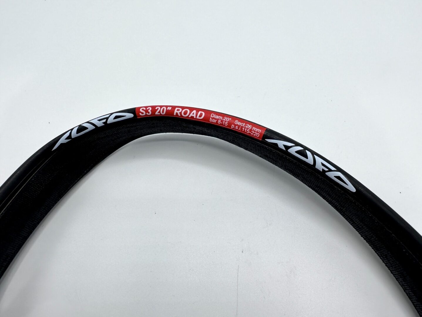 A close up of a T TUFU S3 20 Road Black TUBULAR TIRE on a white surface.