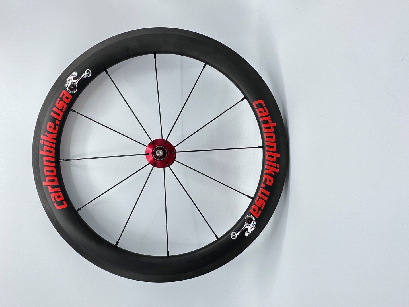 A RW-Carbonbike 20" racing chair wheel with red and black letters on it.