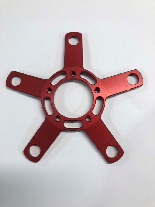 A red H-Spider shaped metal plate on a white surface.