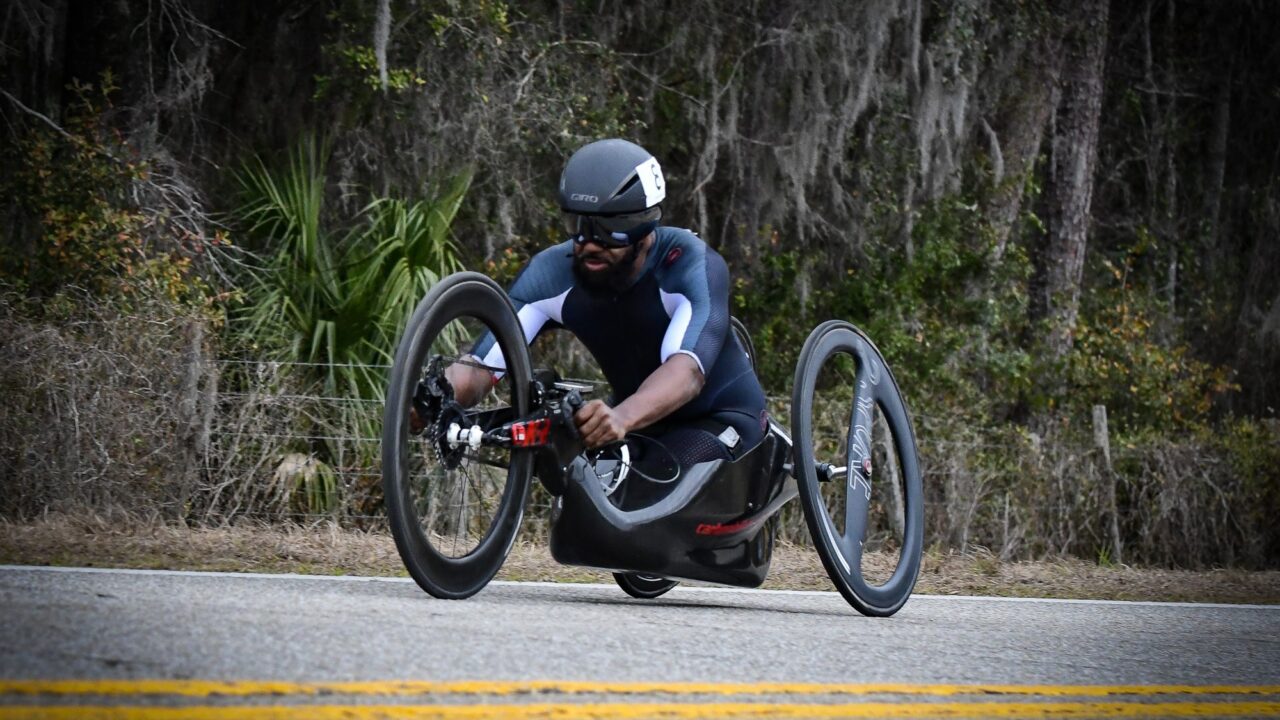 A man wearing black Jersey riding a hand cycle