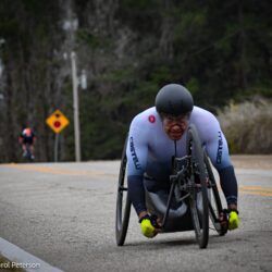 A man in a wheelchair riding down a road.