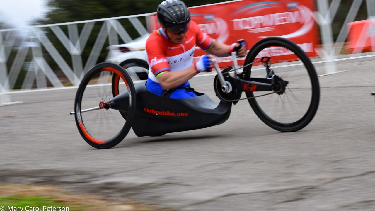 A man wearing red Jersey riding a hand cycle