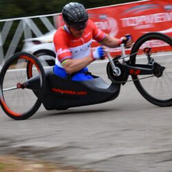 A man wearing red Jersey riding a hand cycle
