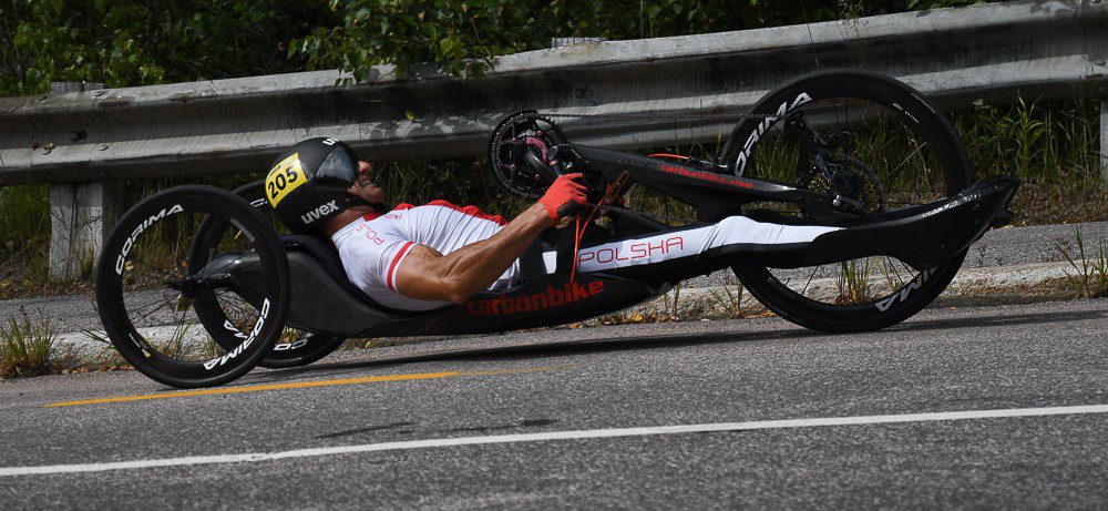 A man riding a hand cycle in white Jersey at high speed