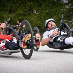 Two men in wheelchairs on a road.