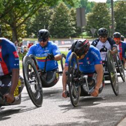 A group of people in wheelchairs racing down a street.
