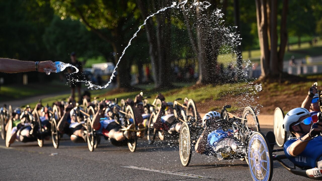 People throwing water on carbon bike riders
