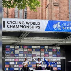 A group of people standing on a stage in front of a sign that says cycling world championships.