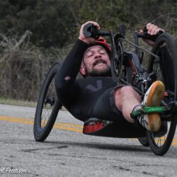 A man in a wheelchair riding down a road.