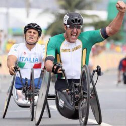 Two men in wheelchairs on a race track.