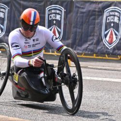 A man in a wheelchair racing down a street.