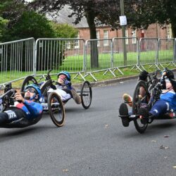 A group of people in wheelchairs racing down a road.